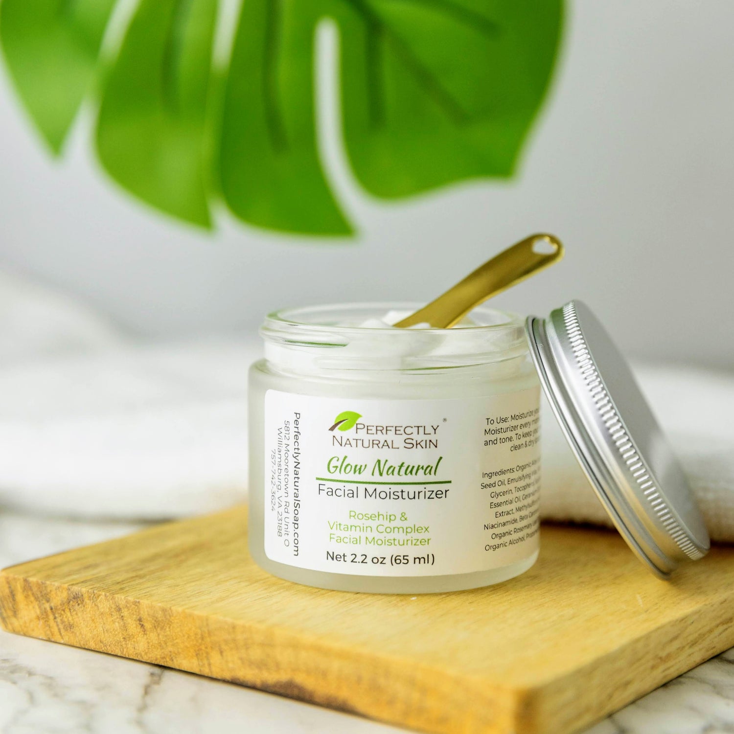 Open Jar of Perfectly Natural Skin Glow Natural Moisturizer with gold spatula showing cream texture