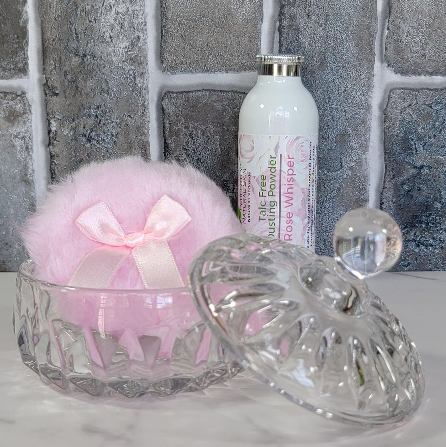 Glass dusting powder jar with powder puff in use, applying natural talc-free body powder after shower