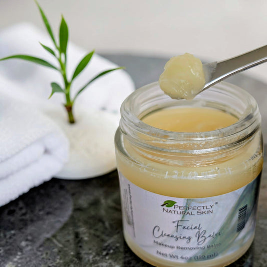 Facial cleansing balm in a jar with a spoonful of balm above it, on a neutral background.